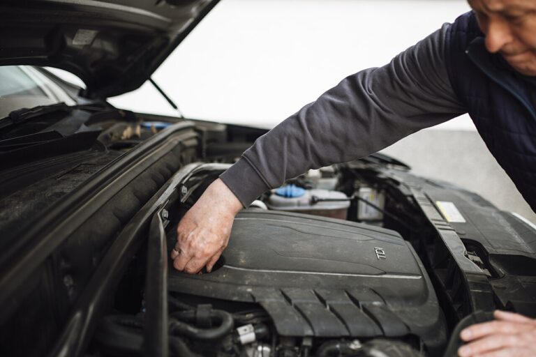 Mechanic working under the open hood of a car